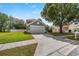 Inviting gray home featuring a two-car garage, mature tree, and well-kept lawn at 3660 Ventura Club Cir, Orlando, FL 32822