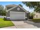Gray home with a two-car garage, white trim, and manicured lawn at 3660 Ventura Club Cir, Orlando, FL 32822