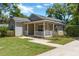 Quaint one-story home featuring a welcoming covered porch, well-maintained lawn, and beautiful landscaping at 441 S Blue Lake Ave, Deland, FL 32724