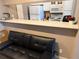 Open living area adjacent to a functional kitchen with bar top and a black leather futon at 510 Cranes Way # 105, Altamonte Springs, FL 32701
