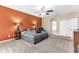 Spacious main bedroom with an orange accent wall, ceiling fan, and neutral carpet flooring at 572 Lanarkshire Pl, Apopka, FL 32712