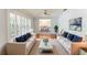 Bright living room with white couches, blue pillows, a white rug, and an entrance to the dining area at 604 Blue Lake Dr, Longwood, FL 32779
