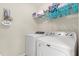 Functional laundry room featuring a modern washer, dryer, storage shelf, and a decorative sign at 660 Egret Place Dr, Winter Garden, FL 34787