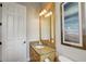 Neutral powder room featuring a wood vanity, granite countertop and framed mirror, located next to a white door at 7388 Gathering Ct, Reunion, FL 34747