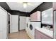 Laundry room with white washer and dryer units, with pink cabinets and black walls at 910 Cypress Ave, St Cloud, FL 34769