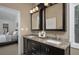 Bathroom boasts double sinks with granite countertop, dark cabinets, and decorative light fixtures at 934 Deerwood Loop, Longwood, FL 32779