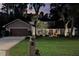 Night shot of a beautifully landscaped home with a well-lit front yard, mature trees, and a two-car garage at 934 Deerwood Loop, Longwood, FL 32779