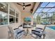 Covered patio featuring a ceiling fan, TV, and outdoor furniture, overlooking the screened pool at 11885 Padua Ln, Orlando, FL 32827