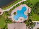 Aerial view of a community pool with an unique shape, lounge chairs, and lush landscaping at 11885 Padua Ln, Orlando, FL 32827