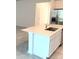 Close-up of the kitchen island with white cabinets and stone countertops, and a stainless steel refrigerator at 1374 Brentwood Dr, Kissimmee, FL 34746