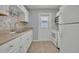 Modern kitchen with white cabinets, stainless steel sink, mosaic backsplash, and access to the backyard at 151 N Orlando Ave # 115, Winter Park, FL 32789