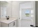 Bathroom with white vanity and door opening to a bright bedroom with large window at 15483 Hamlin Park Drive, Winter Garden, FL 34787