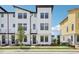 Modern white townhome boasts a stylish design with sleek black accents and lush landscaping for curb appeal at 15483 Hamlin Park Drive, Winter Garden, FL 34787