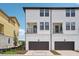 View of white modern townhomes, with brown garage doors and a second story patio at 15483 Hamlin Park Drive, Winter Garden, FL 34787