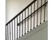 A close-up of a staircase with a dark wood railing and black metal balusters against a white wall at 15483 Hamlin Park Drive, Winter Garden, FL 34787