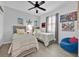 Comfortable ' bedroom with two twin beds, wood-look floors, ceiling fan, and playful decor at 162 Plumoso Loop, Davenport, FL 33897