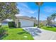 Well-maintained home featuring a lush green lawn, mature trees, and a spacious two-car garage at 162 Plumoso Loop, Davenport, FL 33897