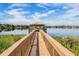 A beautiful dock with a gazebo over a serene lake, surrounded by lush greenery and blue skies at 1803 Glenbay Ct, Windermere, FL 34786