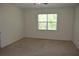 Empty bedroom with a large window, neutral paint, and tan carpet flooring at 245 Brunswick Dr, Davenport, FL 33837