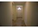 Hallway with neutral color palette leading to the main entrance door and tiled flooring at 245 Brunswick Dr, Davenport, FL 33837