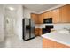 Well-lit kitchen featuring oak cabinets, stainless refrigerator, and black appliances at 3542 Shallot Dr # 108, Orlando, FL 32835