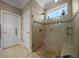 This shower features a glass door, neutral tile, a pebble floor, and a shower bench at 4687 Nw 35Th Lane Rd, Ocala, FL 34482