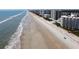 Wide aerial shot of the coastline showing the beach, ocean, and nearby buildings at 5203 S Atlantic Ave # 416B, New Smyrna Beach, FL 32169