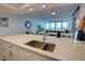 Bright kitchen features white cabinets, stone countertops, and stainless steel sink with ocean view at 5203 S Atlantic Ave # 416B, New Smyrna Beach, FL 32169