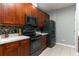 Close-up of a kitchen highlighting dark wood cabinets, black appliances, and a tiled backsplash for a modern touch at 558 Pinebranch Cir, Winter Springs, FL 32708