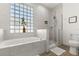 Well-lit bathroom featuring a tub and separate shower, with patterned tile and a glass block window at 581 Hollingshead Loop, Davenport, FL 33896