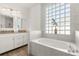 Bathroom featuring a soaking tub under a glass block window and a double sink at 581 Hollingshead Loop, Davenport, FL 33896