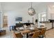 Dining area features a rustic wood table, modern chandelier, and open layout connected to the living room at 581 Hollingshead Loop, Davenport, FL 33896