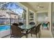A covered outdoor patio features a dining table, chairs, and a pool view at 581 Hollingshead Loop, Davenport, FL 33896