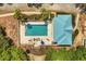 Aerial view of the community pool featuring a vibrant blue pool, a cabana, lounge chairs, and landscaping at 581 Hollingshead Loop, Davenport, FL 33896