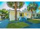 Inviting yellow home featuring a covered front porch, manicured lawn, and two mature palm trees at 611 Sanford Ave, Sanford, FL 32771