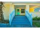 Welcoming front porch with a blue door, light yellow siding, and a freshly painted blue staircase at 611 Sanford Ave, Sanford, FL 32771