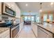 Open kitchen with white cabinets, granite countertops and stainless steel appliances with view to dining area at 6807 Habitat Dr, St Cloud, FL 34773