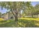 Landscaped backyard with a mature tree, lawn, and grill at 7167 Winding Lake Cir, Oviedo, FL 32765