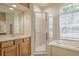 Well-lit bathroom features a glass-enclosed shower, garden tub, and wooden vanity with large mirror at 7167 Winding Lake Cir, Oviedo, FL 32765