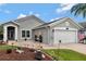 Charming gray home featuring a two-car garage, arched entry, and beautifully landscaped front yard at 725 High Vista Dr, Davenport, FL 33837