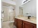 Bathroom with a walk-in shower with glass doors, wooden vanity, and neutral countertops at 7264 Hawksnest Blvd, Orlando, FL 32835