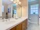 Bathroom featuring double sinks, wooden cabinetry, a decorative mirror, and a separate toilet room at 7409 Excitement Dr, Reunion, FL 34747