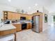 Well-lit kitchen with stainless steel appliances, tile backsplash, and light wood cabinetry at 7409 Excitement Dr, Reunion, FL 34747