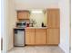 A well-lit kitchenette is shown, with light wooden cabinets, a small fridge, and a microwave at 7409 Excitement Dr, Reunion, FL 34747