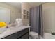 This bathroom features a single vanity with black cabinetry, white countertops, and a shower-tub with a gray shower curtain at 8844 Cabot Cliffs Dr, Davenport, FL 33896