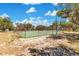View of tennis court with green playing surface surrounded by a tall fence at 9143 San Ambrosio, Orlando, FL 32836