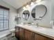 A double sink bathroom vanity with wood look tile flooring, round mirrors, and decorative plants at 998 Piedmont Oaks Dr, Apopka, FL 32703