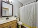 Neutral toned bathroom features a framed mirror, vanity, and striped shower curtain at 998 Piedmont Oaks Dr, Apopka, FL 32703