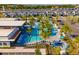 A resort pool is surrounded by lounge chairs, umbrellas, palm trees, well manicured shrubs, and neighborhood townhomes at 10436 Ebb Tide Lane, Orlando, FL 32821