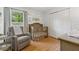 Bedroom featuring a grey rocking chair, crib, wood laminate floors, and white walls at 1118 Brielle Ct, Oviedo, FL 32765